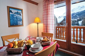 Ein Esstisch mit Früchten, Brot und Blick auf schneebedeckte Berge.