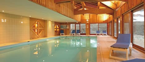 Una piscina interior con paredes de madera y ventanas amplias.
