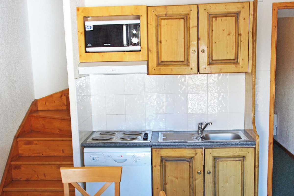 A compact kitchen with wooden cabinets, a microwave, a dishwasher, a stove, and a sink.