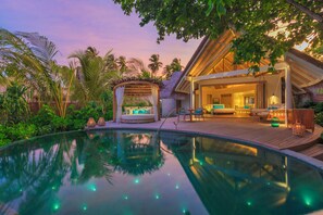 A resort with a swimming pool, a covered seating area, and a well-lit interior. - Milaidhoo Island Maldives (Milaidhoo Island)
