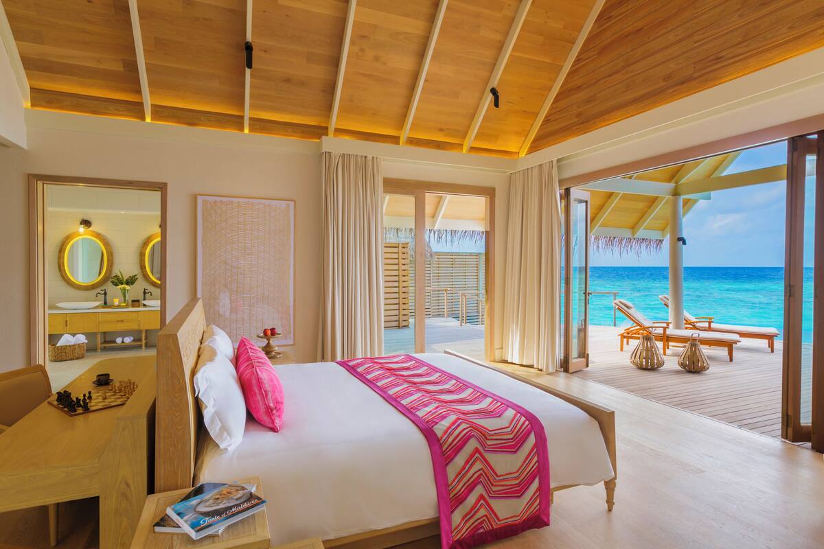 Una habitación de hotel con cama, escritorio, espejo y vista al océano.