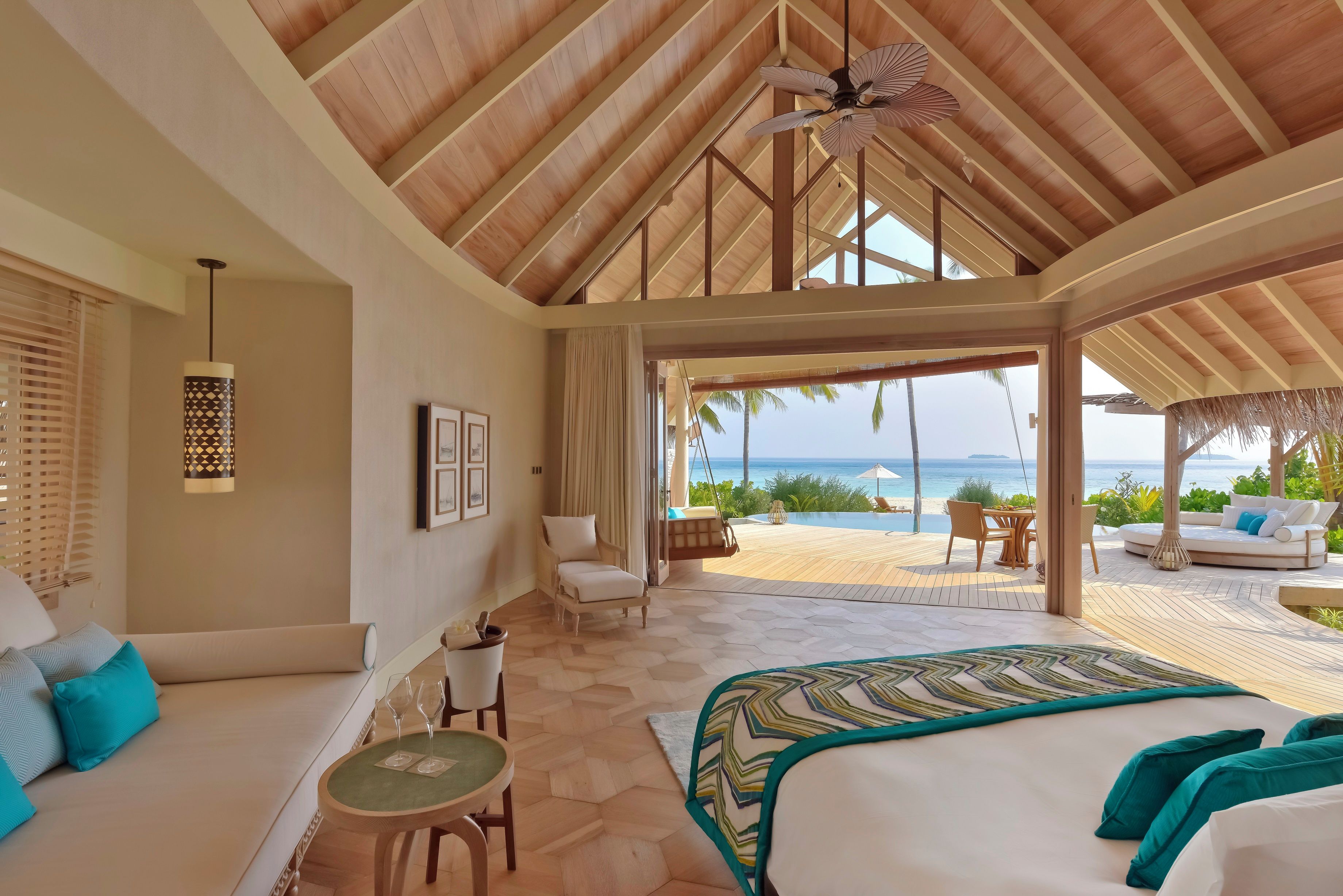 A spacious room with a large bed, a seating area with a table, and a view of the beach.
