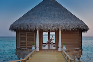 A wooden structure with a thatched roof, a wooden deck, and a view of the ocean.