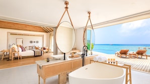 A modern bathroom with a freestanding bathtub, wooden vanity, and large mirrors. - Milaidhoo Island Maldives (Milaidhoo Island)