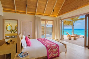 Quarto de hotel com uma cama, uma escrivaninha, um espelho e vista para o oceano.