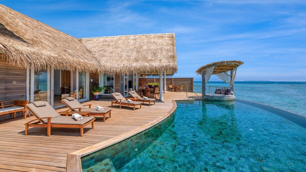 A resort with a pool, lounge chairs, and a thatched-roof structure. - Milaidhoo Island Maldives (Milaidhoo Island)