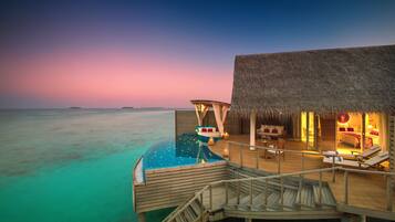 A resort overwater bungalow with a private pool, wooden deck, and thatched-roof lounge area.