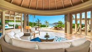 A spacious living area with a curved ceiling, large windows, and a view of the ocean. - Milaidhoo Island Maldives (Milaidhoo Island)
