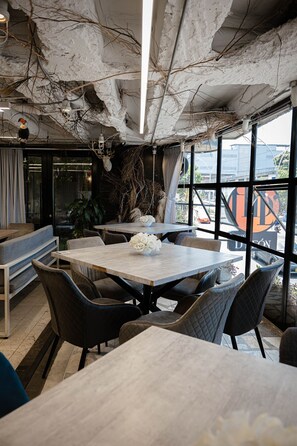 An interior with a rustic ceiling, a dining area with a table and chairs, and a view through large windows. - Hotel D' Leon (Floridablanca)