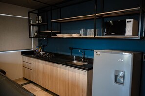 A compact kitchen with a stove, sink, and a refrigerator.