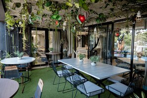An indoor patio with tables and chairs, surrounded by greenery and plants. - Hotel D' Leon (Floridablanca)