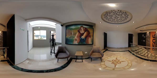 Un moderno vestíbulo con un mural grande, una escalera y vistas de la ciudad.