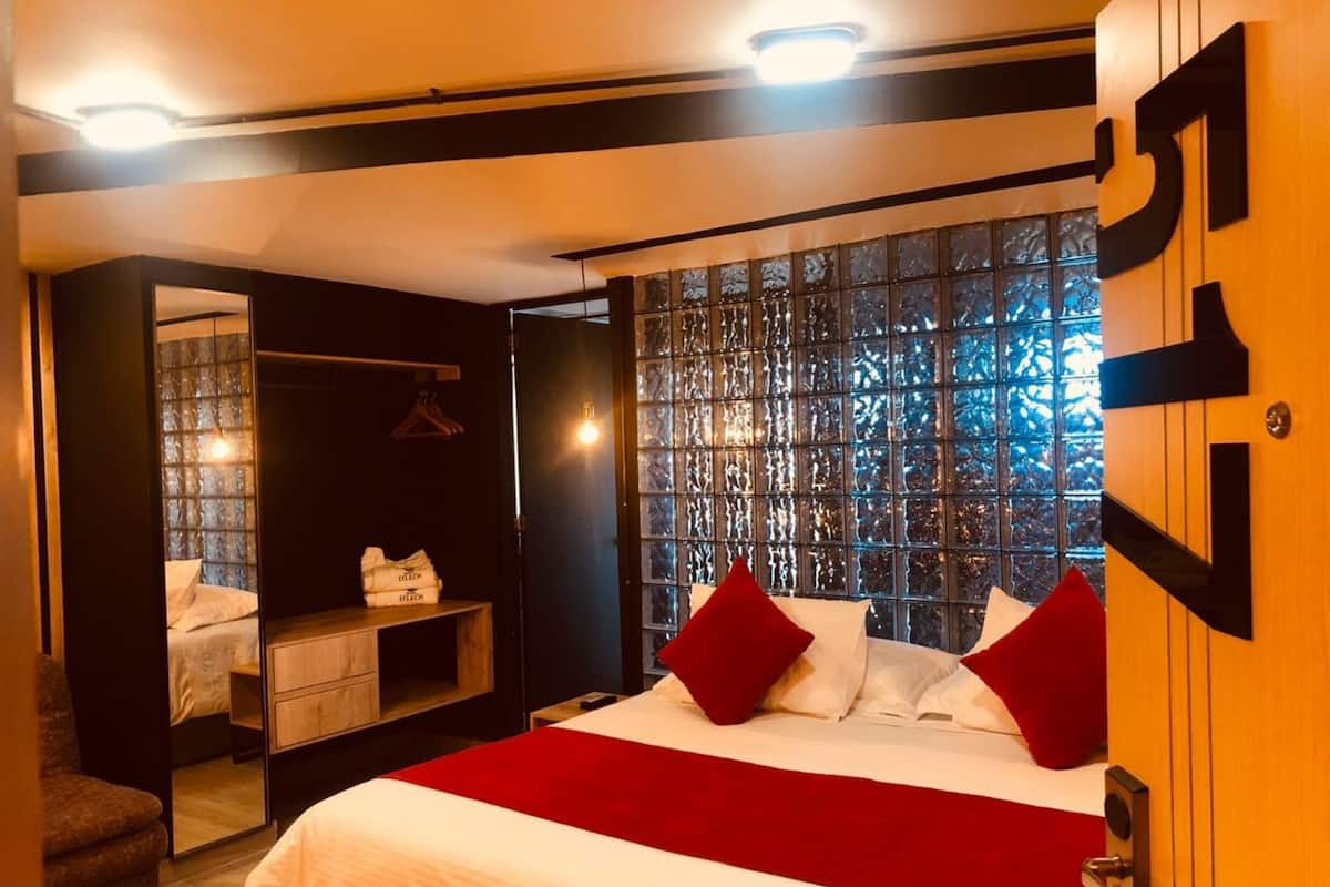 Quarto de hotel com cama, guarda-roupa, espelho e janela com vista.