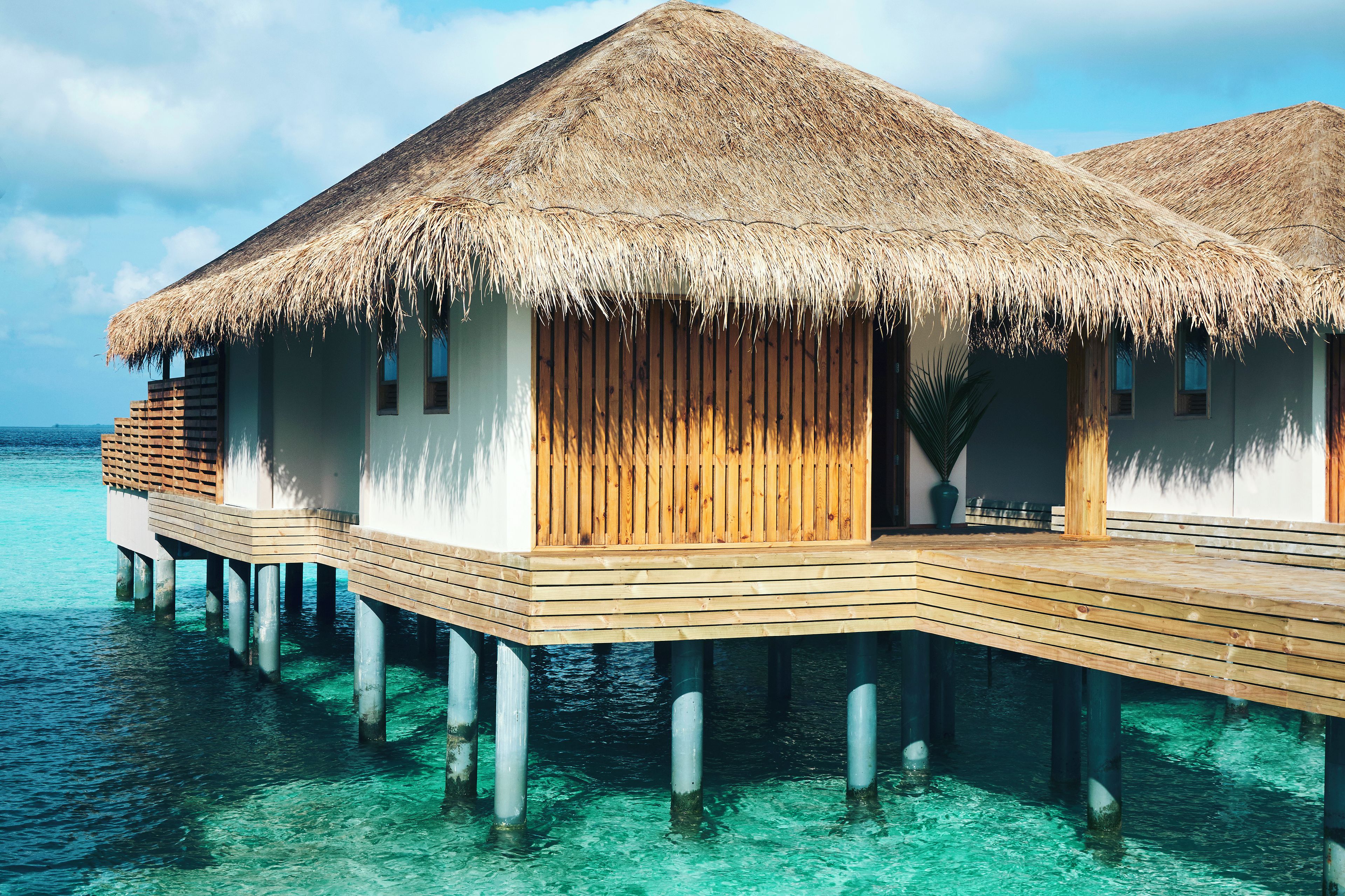 Cabañas sobre el agua con techos de paja y balcones de madera.