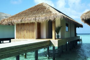Overwater bungalows with thatched roofs, wooden walkways, and clear blue water. - Kudafushi Resort & Spa (Kudafushi)