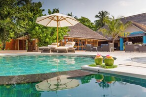 A pool area with lounge chairs, a thatched-roof structure, and a tropical setting. - Kudafushi Resort & Spa (Kudafushi)