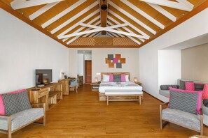 A hotel room with a wooden ceiling, a bed with patterned pillows, a desk with a computer, and a TV. - Kudafushi Resort & Spa (Kudafushi)