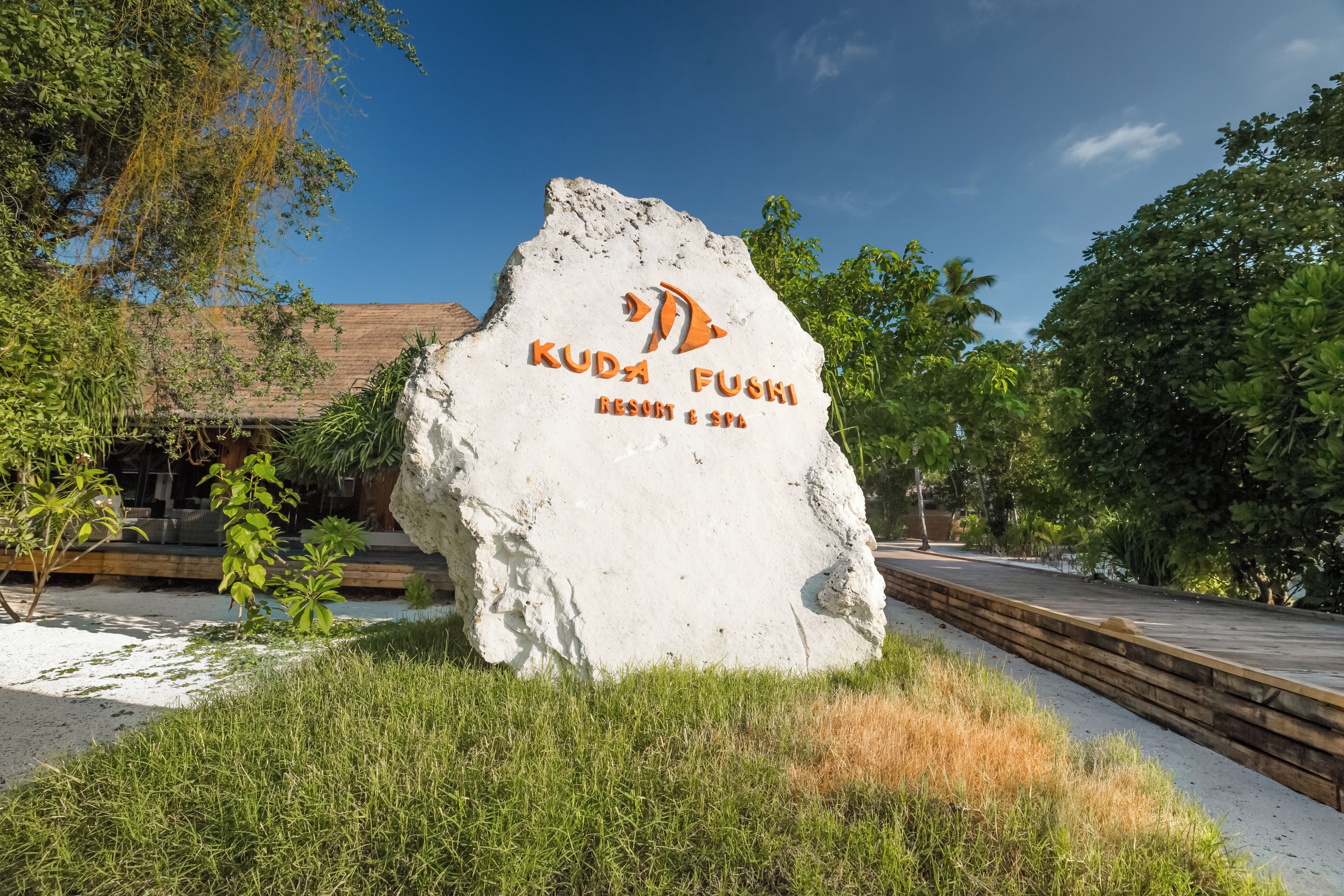 A large white rock with the text "Kuda Fushi Resort & Spa" and a logo.