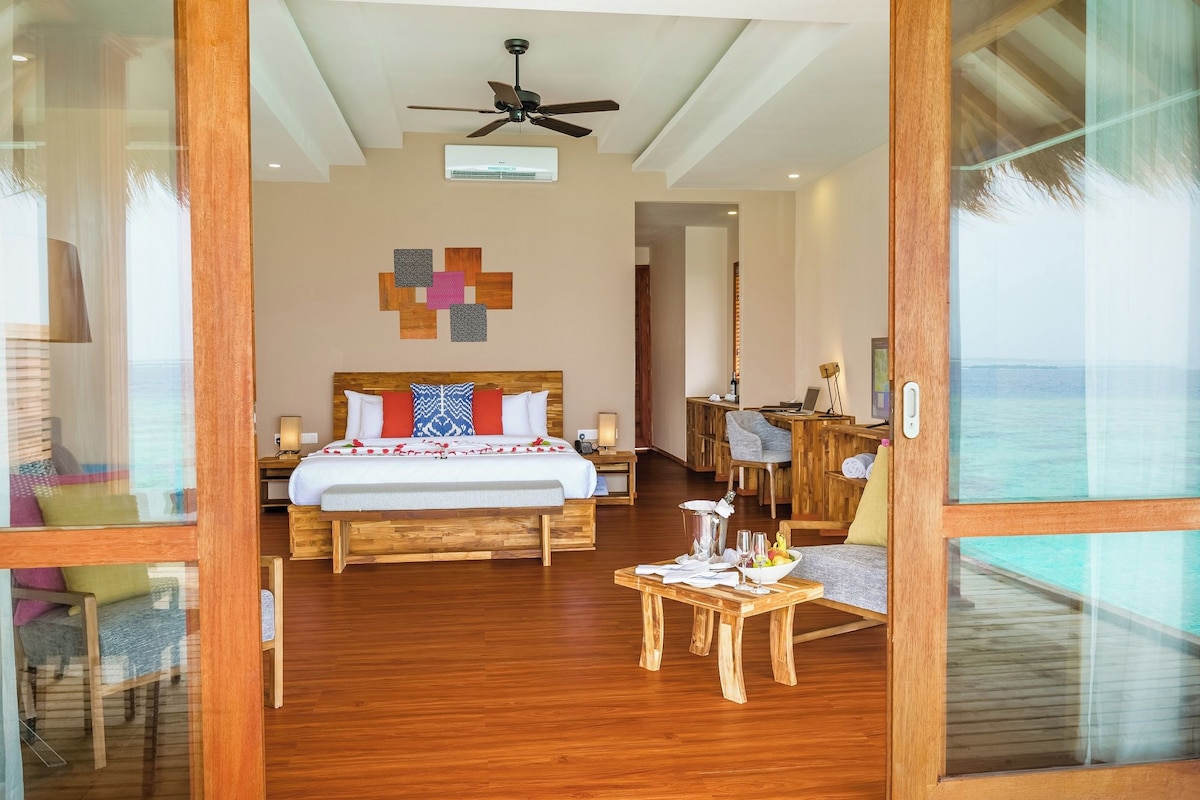 A hotel room with a bed, a desk, a chair, and a view of the ocean.