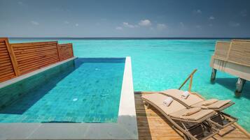 A clear blue pool with wooden deck and lounge chairs.