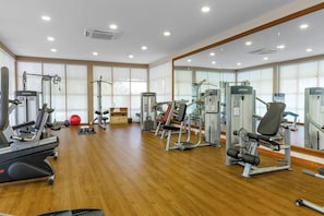 A gym with various exercise machines, a red exercise ball, and wooden flooring. - Kudafushi Resort & Spa (Kudafushi)