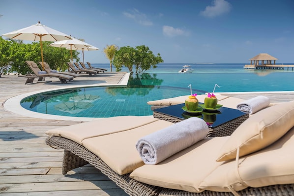 A poolside area with lounge chairs, umbrellas, and a view of the ocean. - Kudafushi Resort & Spa (Kudafushi)