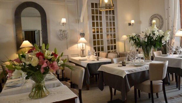 A dining area with tables set for service, a mirror, and wall-mounted lamps.