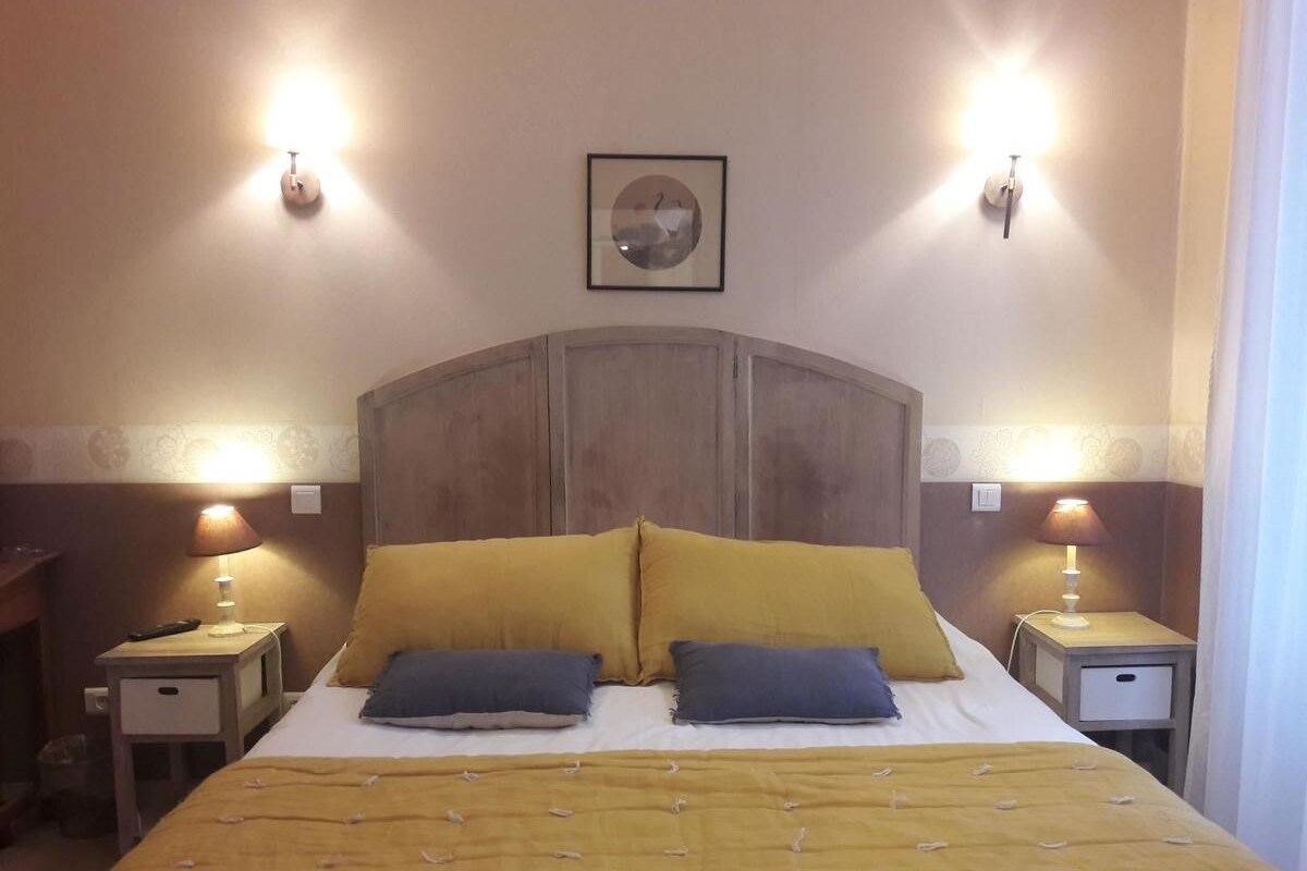 A hotel room with a bed, two bedside tables, two lamps, and a framed picture on the wall.