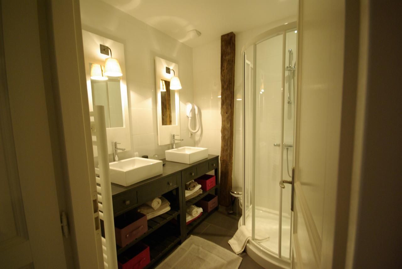 Een badkamer met twee wastafels, een spiegel, een douche en een handdoekrek.