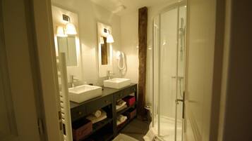 Een badkamer met twee wastafels, een spiegel, een douche en een handdoekrek.