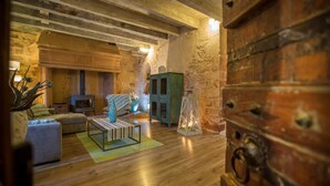 A rustic interior with exposed beams, a fireplace, a sofa, a coffee table, and a cabinet.