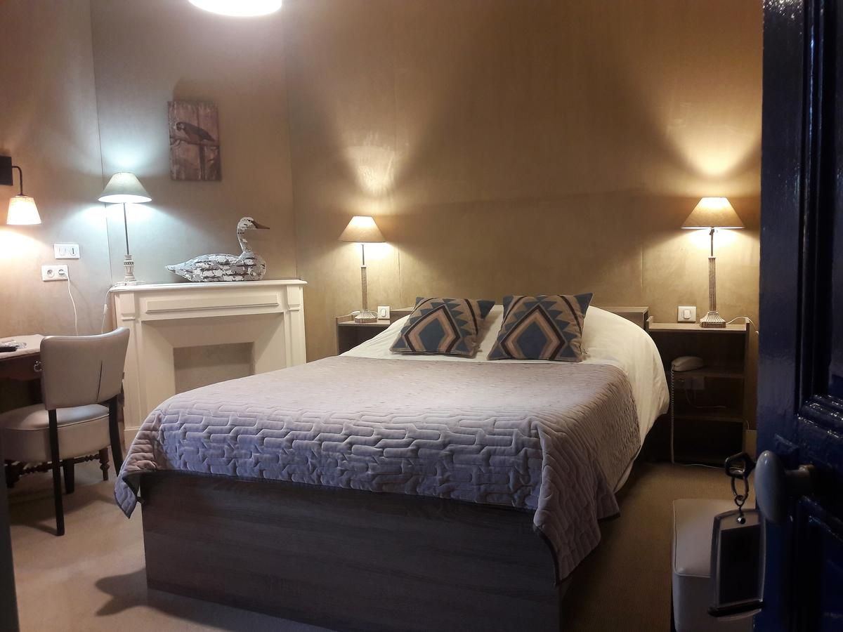 Een slaapkamer met een bed, twee nachtkastjes, een bureau, een stoel en een open haard.