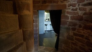 A stone staircase leading to a room with a white door and a bar area visible through an open door.