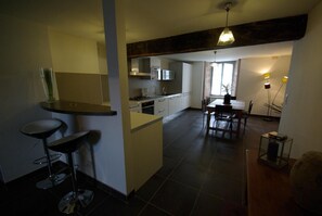 A modern kitchen with a bar area, a dining table, and a view of the living area.