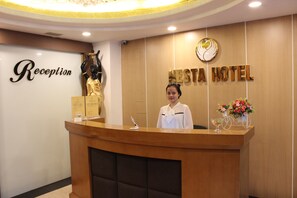 A reception desk with a 'Reception' sign, a 'NESTA HOTEL' sign, and a receptionist. - Nesta Boutique Hotel Hanoi (Hanoi)