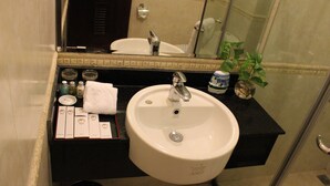 A bathroom with a white sink, a mirror, a black countertop, and a small plant. - Nesta Boutique Hotel Hanoi (Hanoi)