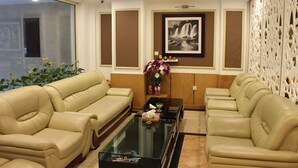 A room with two beige sofas, a glass coffee table, a framed black and white photo, and a decorative white partition. - Nesta Boutique Hotel Hanoi (Hanoi)