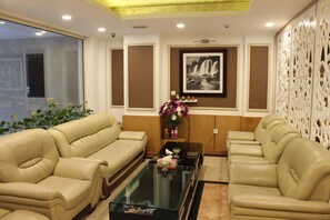A room with two beige sofas, a glass coffee table, a framed black and white photo, and a decorative white partition. - Nesta Boutique Hotel Hanoi (Hanoi)