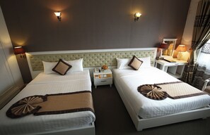 A hotel room with two beds, a tufted headboard, bedside lamps, a nightstand with a phone, and a window with curtains. - Nesta Boutique Hotel Hanoi (Hanoi)