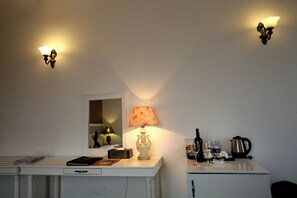 A room with a white desk, a lamp, a mirror, and a cabinet with bottles and a kettle. - Nesta Boutique Hotel Hanoi (Hanoi)