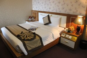 A hotel room with a neatly made bed, a bedside table with a lamp, a telephone, and a small vase with flowers. - Nesta Boutique Hotel Hanoi (Hanoi)