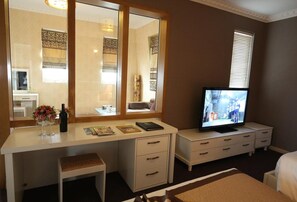 A hotel room with a large mirror, a television, a desk with drawers, a small bench, and a window with blinds. - Nesta Boutique Hotel Hanoi (Hanoi)