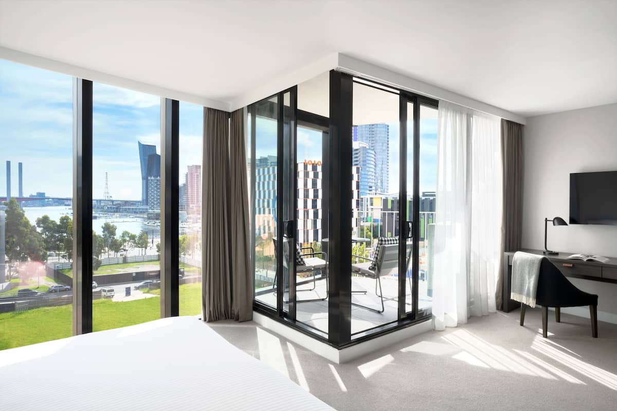 Een moderne hotelkamer met een groot raam, een bed, een bureau en een stoel.