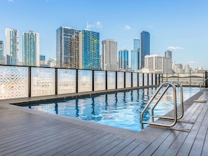 Une piscine sur le toit, avec la vue sur les toits de la ville en arrière-plan.