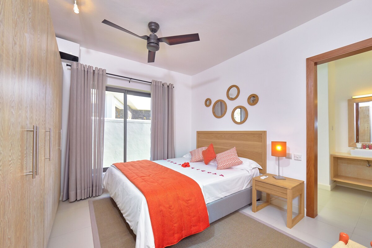 Ein Hotelzimmer mit Bett, Nachttisch, Spiegel und Deckenventilator.