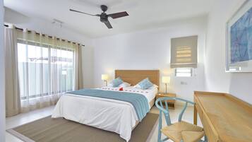 A hotel room with a bed, a desk, a chair, a ceiling fan, and a window with curtains.
