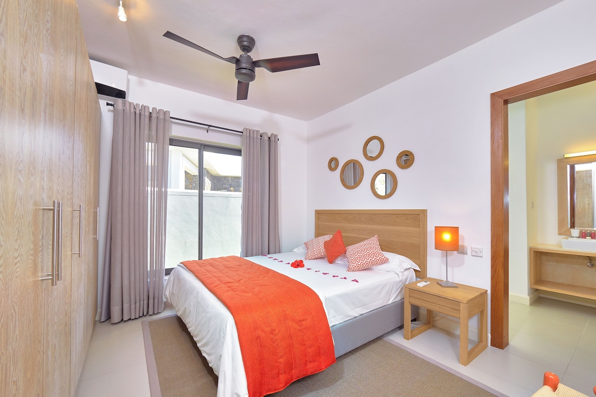 A hotel room with a bed, a nightstand, a mirror, and a ceiling fan.