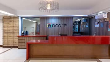 A reception area with a red desk, a modern chandelier, and a wall-mounted air conditioner.