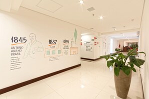 Un couloir orné d’une frise murale retraçant l’histoire, d’une plante en pot et d’un panneau indiquant l’emplacement d’un restaurant.