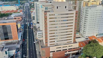 Um hotel de vários andares com design moderno, apresentando uma entrada imponente, um pátio central e vista para a paisagem urbana circundante.